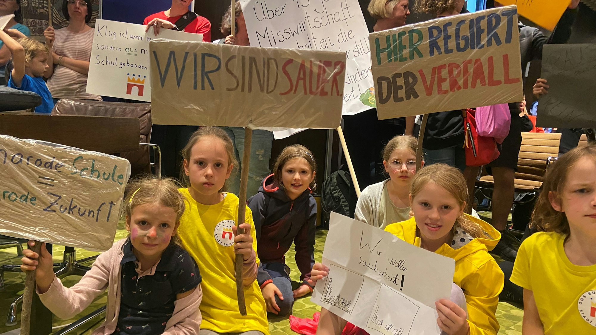 Kinder halten selbst gemalte Plakate mit Forderungen hoch.
