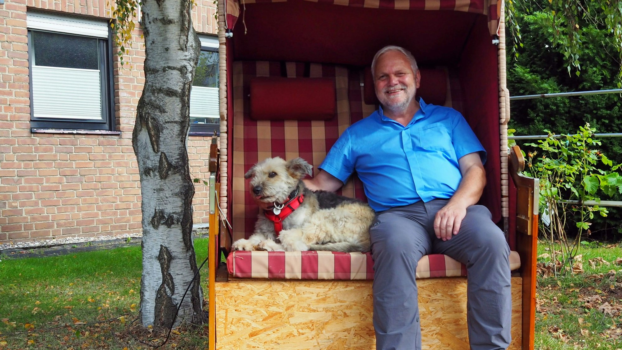 Pfarrer Hittmeyer sitzt mit seinem Hund in einem Strandkorb.