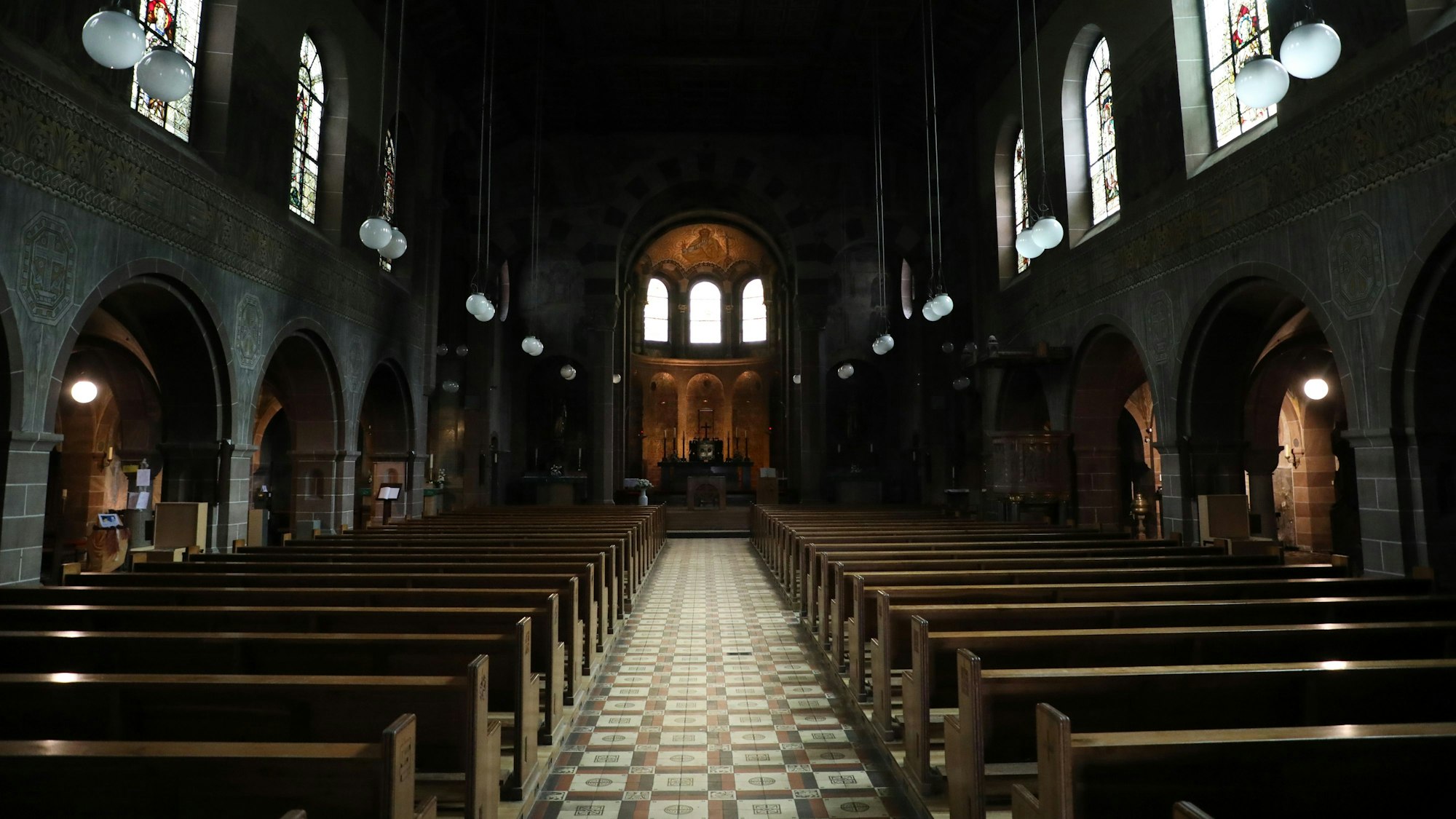 Blick in ein dunkles Kirchenschiff der Kirche St. Laurentius in Bergisch Gladbach.