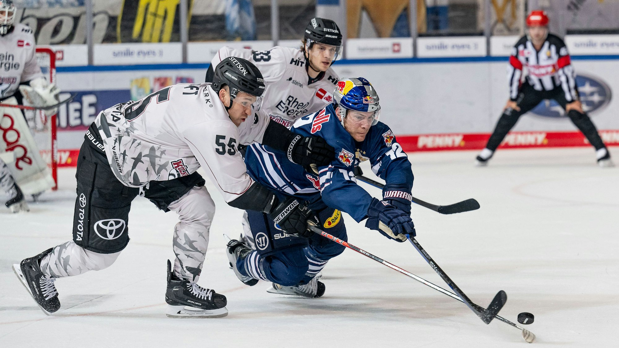 Carter Proft und Tim Wohlgemuth von den Kölner Haien und Ben Smith vom EHC München kämpfen um den Puck.