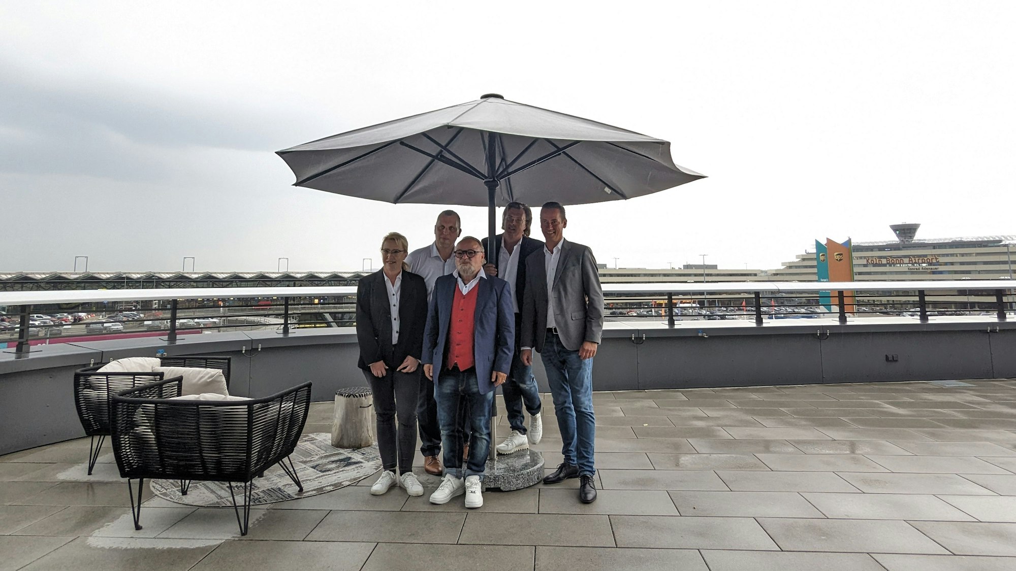 Gruppenbild auf einer Terrasse, im Hintergrund der Kölner Flughafen