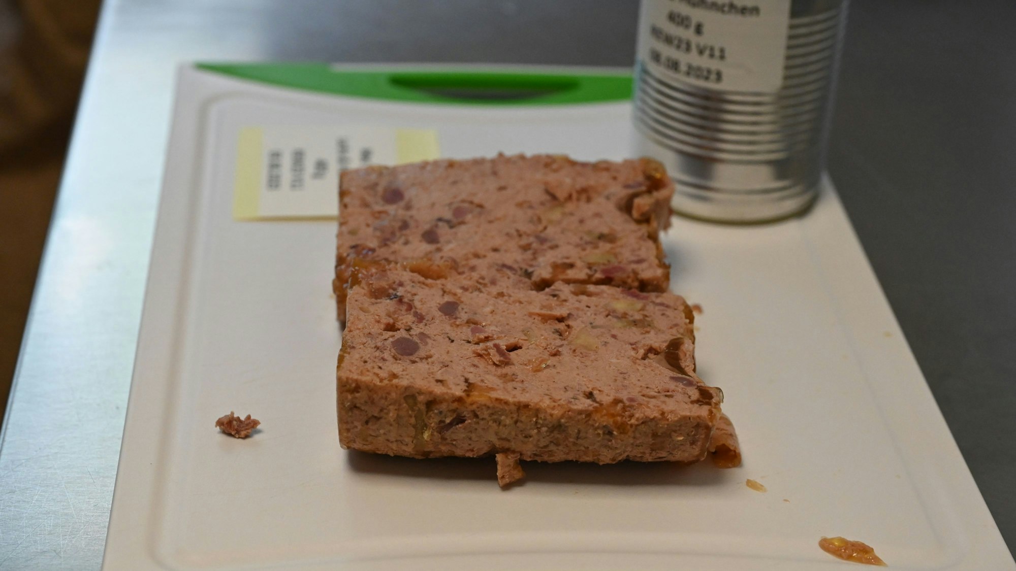 Der Inhalt einer Tierfutter-Dose liegt in zwei Hälften zerteilt auf einem Schneidbrett. Die Konsistenz erinnert an eine Pastete.