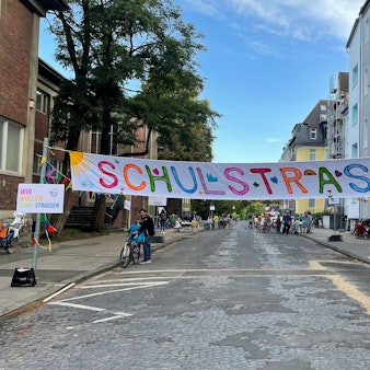 Banner „Schulstraße“ über einer Straße in Köln.