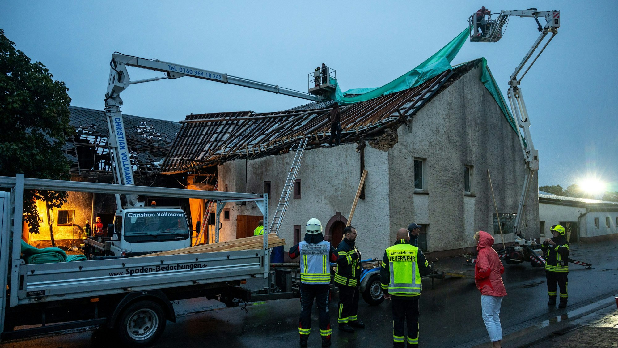 Feuerwehr und Einsatzkräfte kämpfen mit Schäden an einem abgedeckten Häuserdach im rheinland-pfälzischen Nusbaum, die durch einen Tornado verursacht wurden.