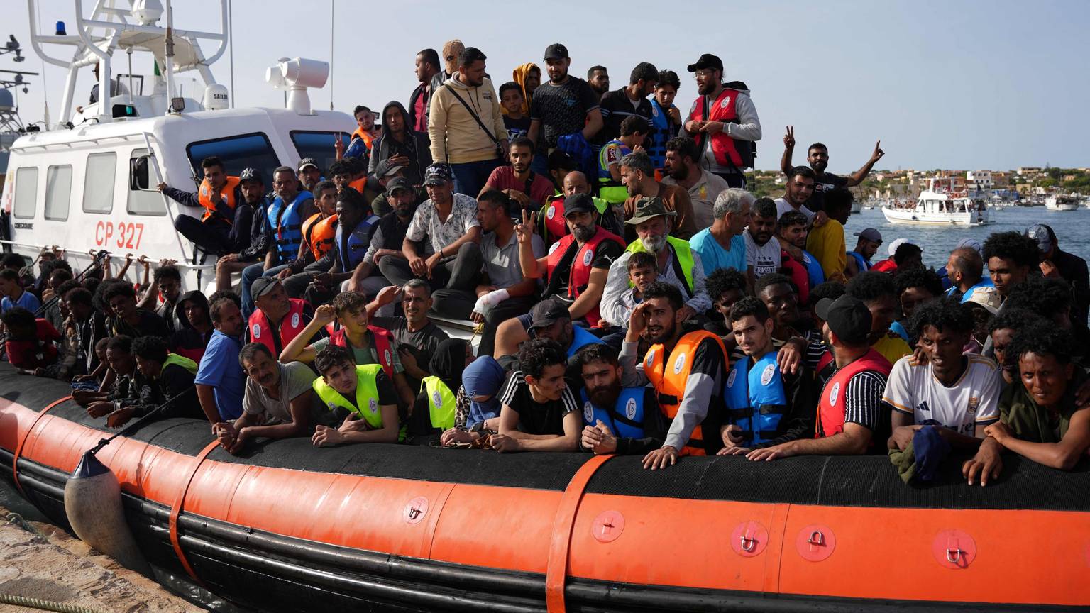 Migranten kommen auf einem Schlauchboot im Hafen von Lampedusa an.