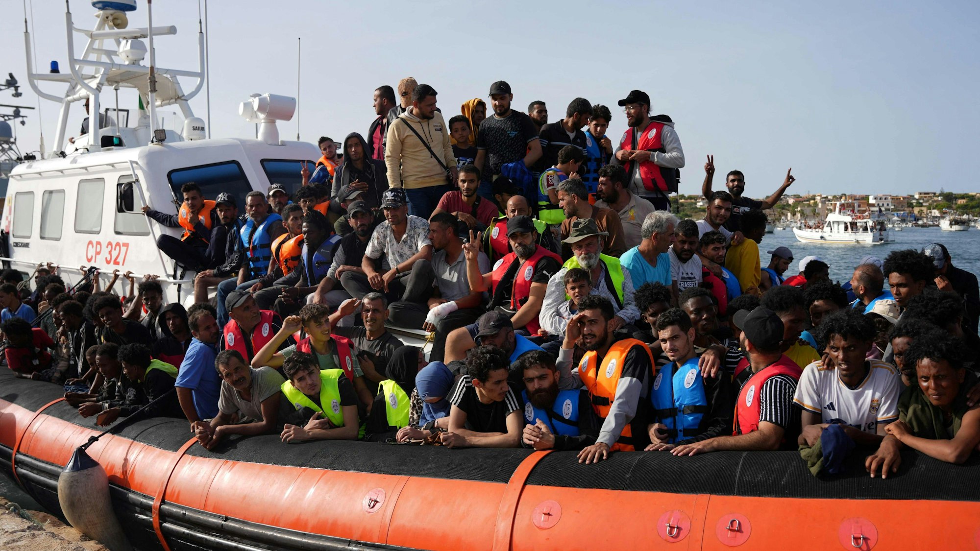 Migranten kommen auf einem Schlauchboot im Hafen von Lampedusa an.