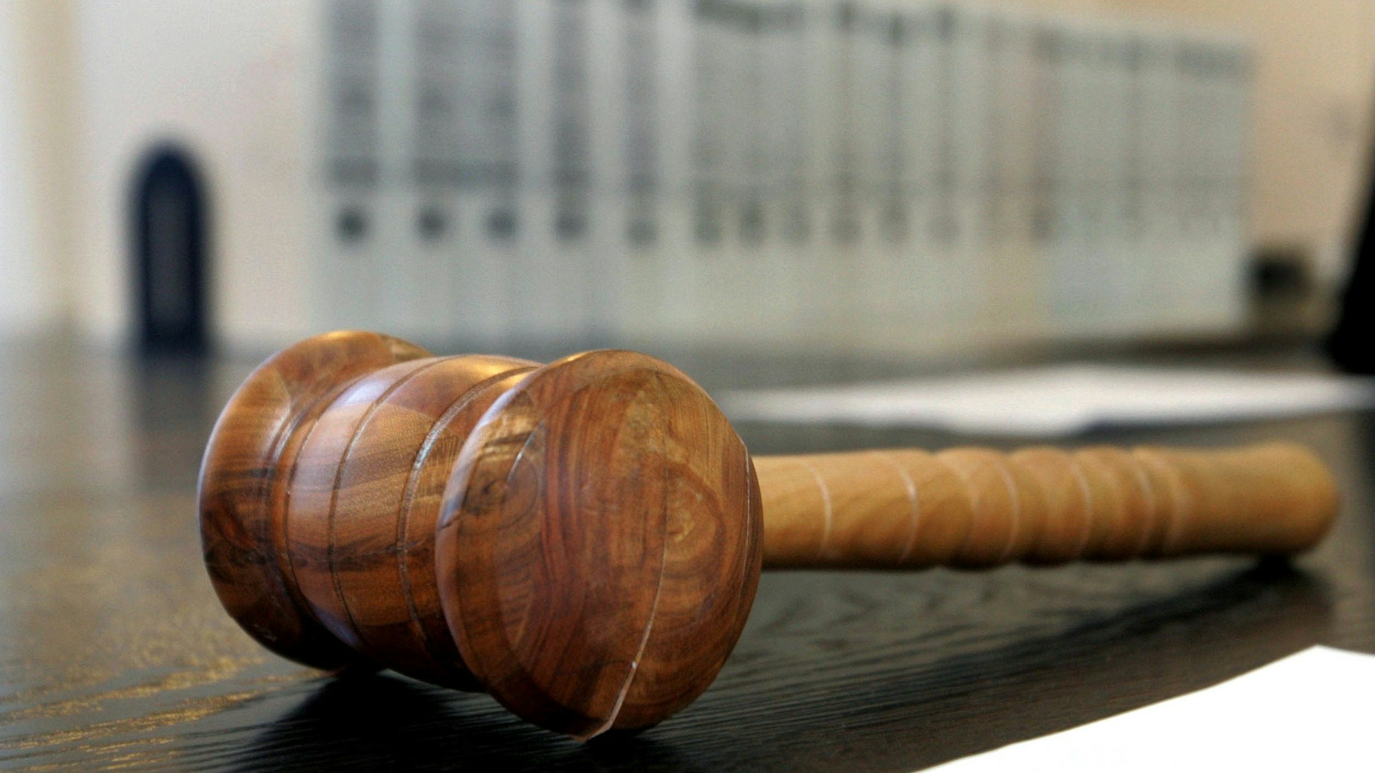 Ein hölzerner Hammer liegt auf der Richterbank in einem Verhandlungssaal.