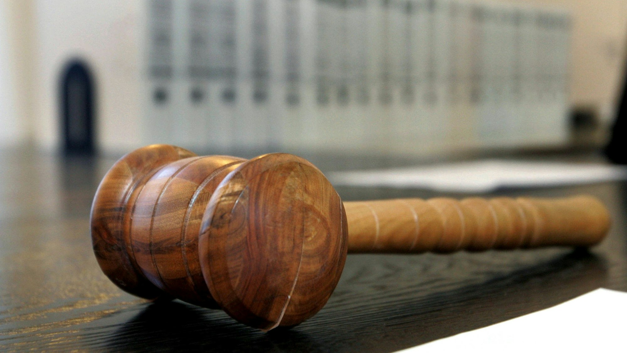 Ein hölzerner Hammer liegt auf der Richterbank in einem Verhandlungssaal.