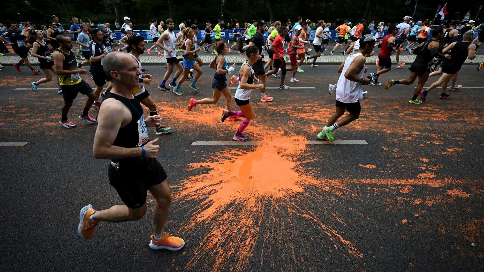 dpatopbilder - 24.09.2023, Berlin: Leichtathletik: Berliner Marathon. Teilnehmer des Marathon laufen durch die orangefarbene Farbe, die von Aktivisten der Klimaschutzgruppe "Letzte Generation" bei einer Protestaktion auf den Asphalt geschüttet wurde. Foto: Sebastian Christoph Gollnow/dpa +++ dpa-Bildfunk +++