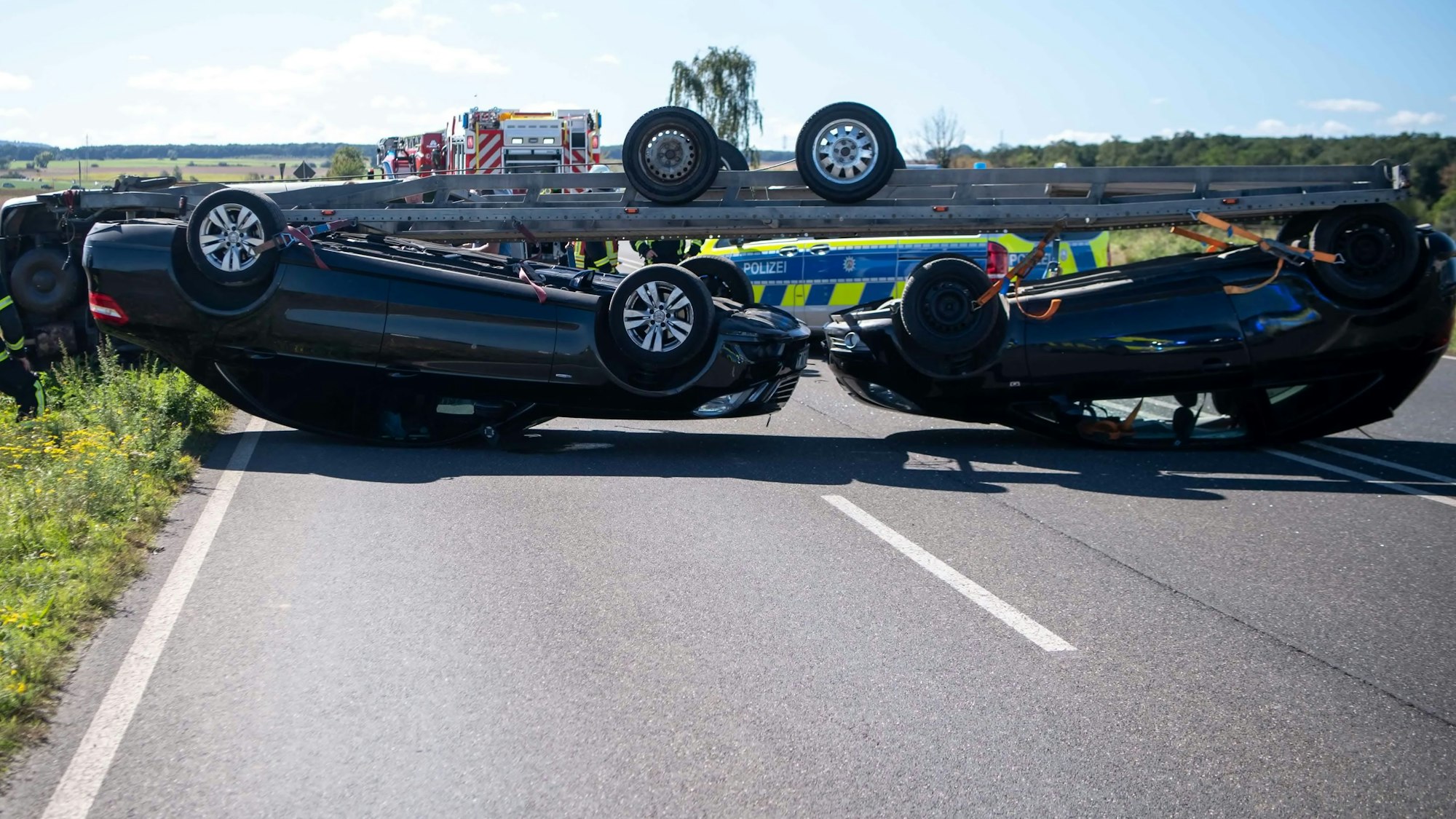 Das Bild zeigt den umgekippten Anhänger mit zwei Autos.