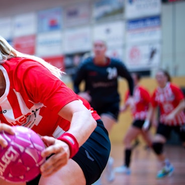 Eine Handballspielerin sich sich den Ball.