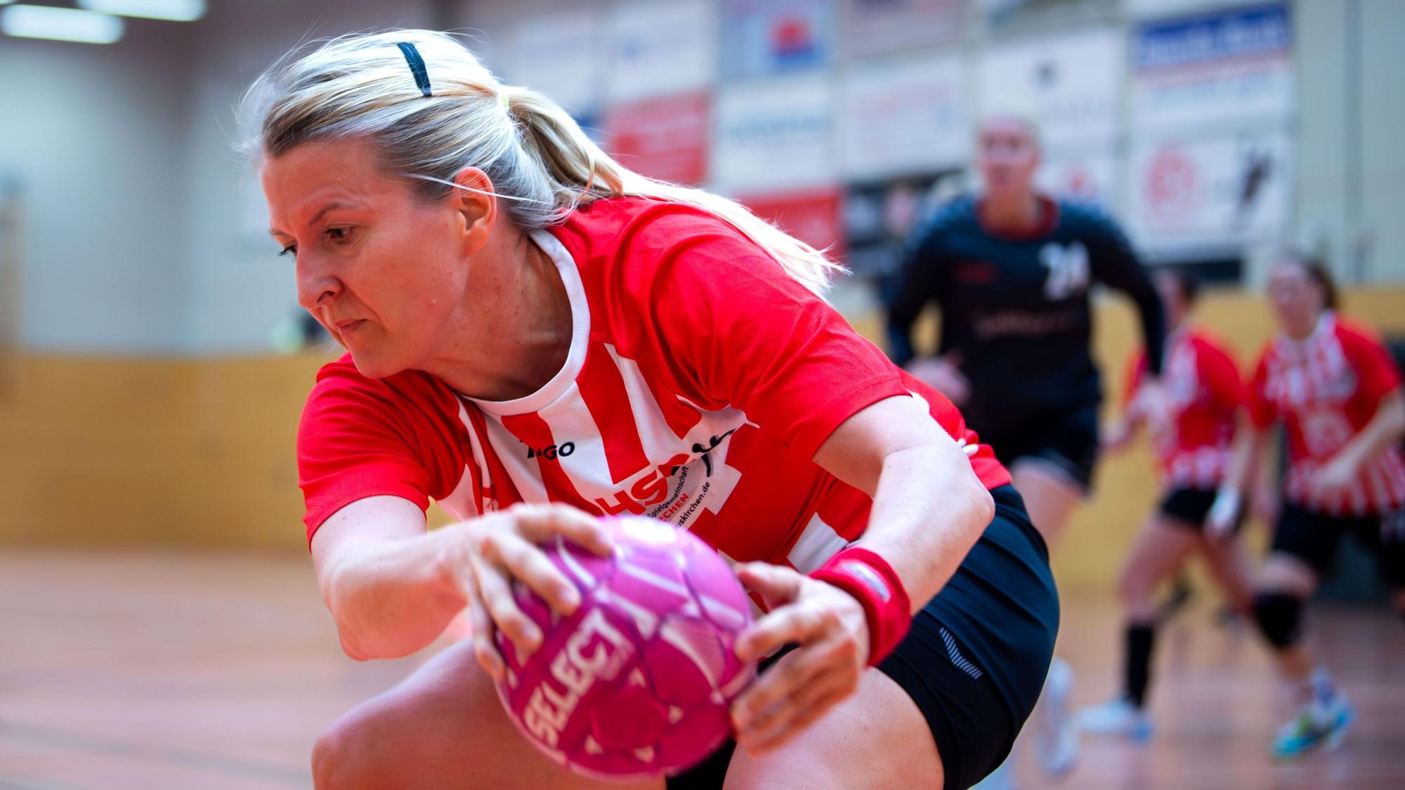 Eine Handballspielerin sich sich den Ball.