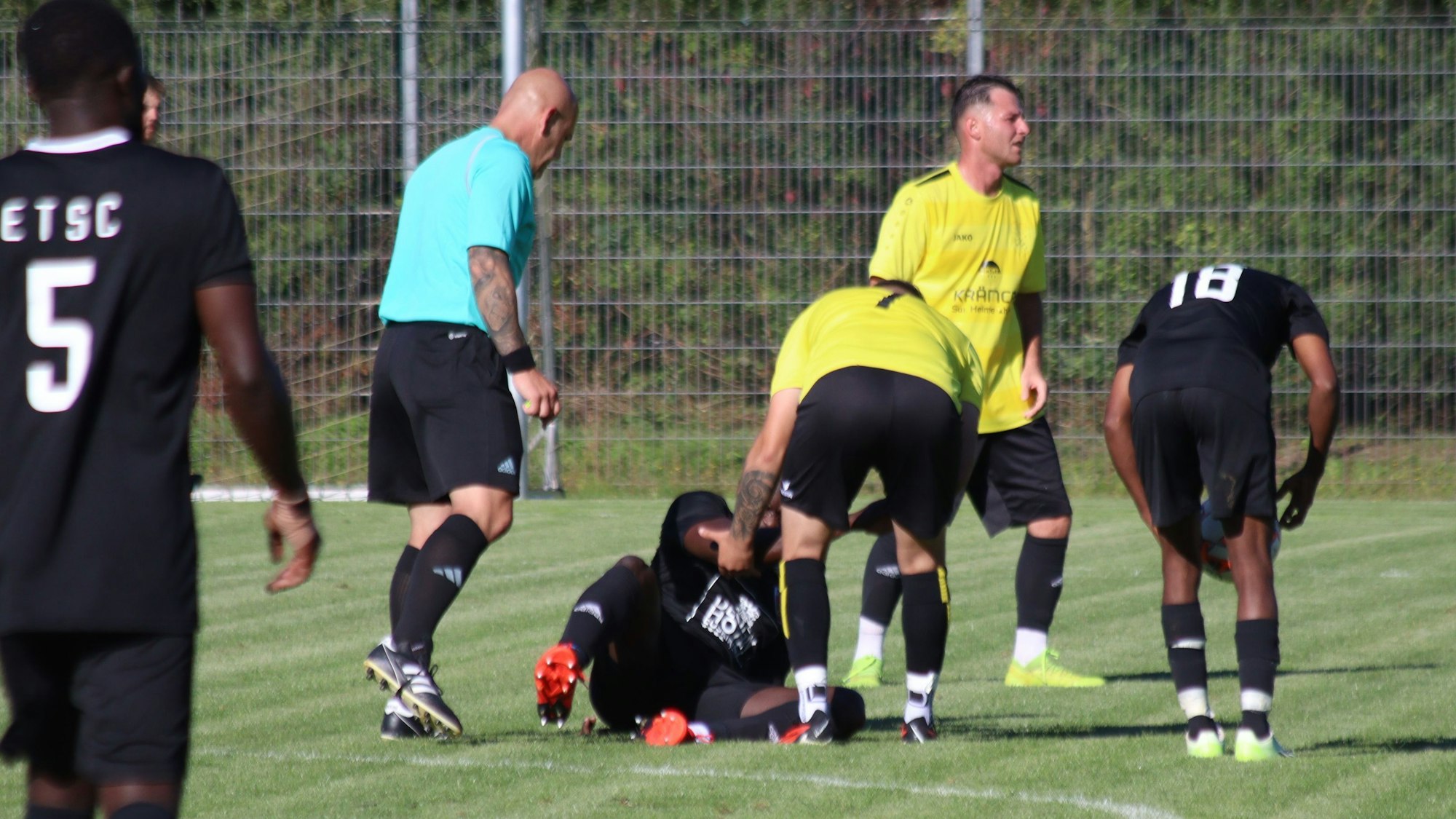 Ein Fußballer hilft einem Gegner beim Aufstehen.