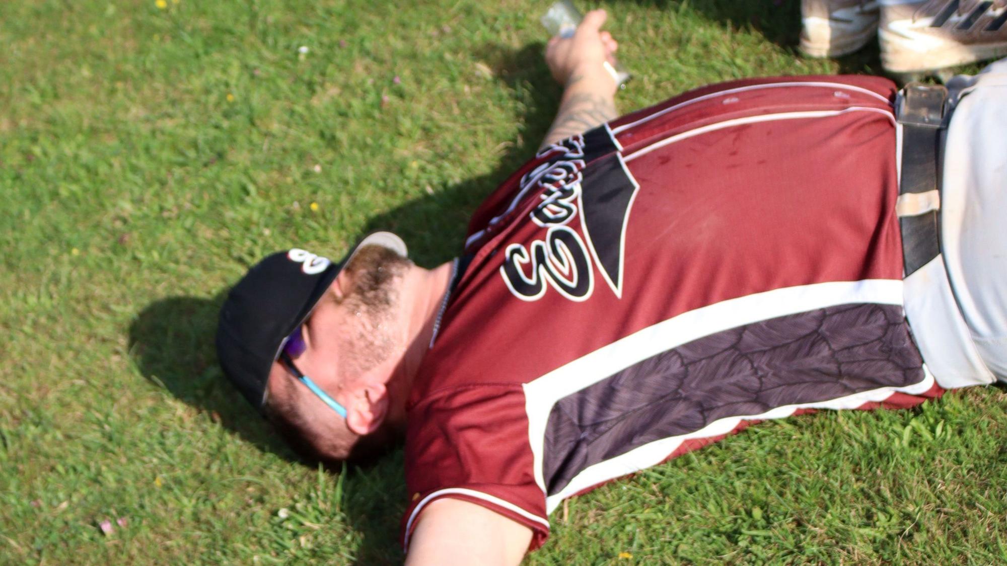 Ein Baseball-Spieler liegt mit ausgebreiteten Armen auf dem Gras.