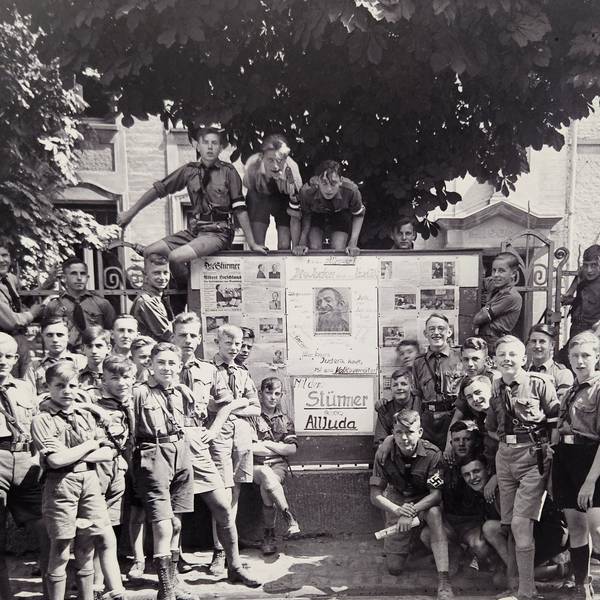 Jungen in HJ-Uniformen stehen vor einem großen Schaukasten.