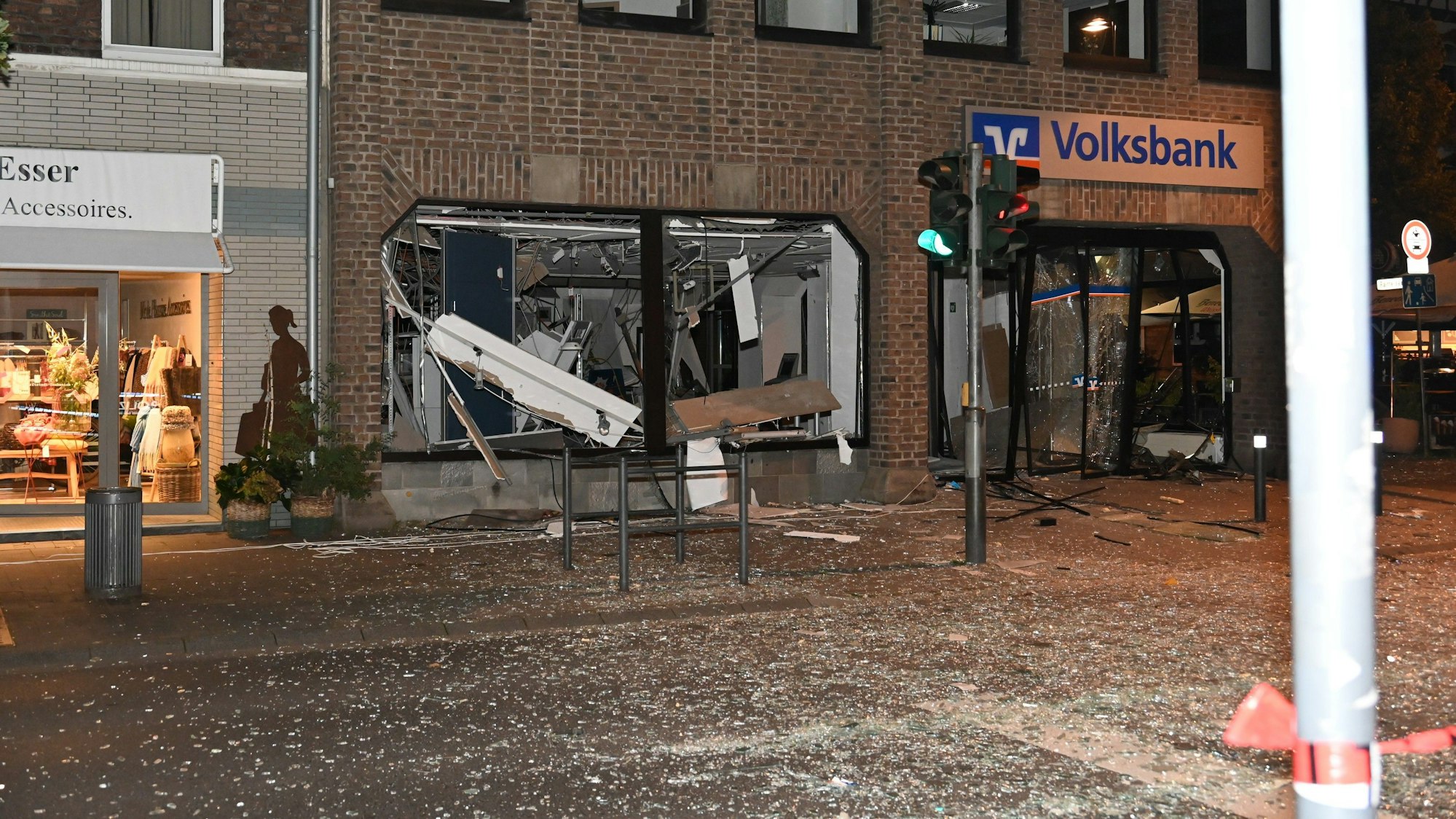 Scherben liegen auf der Straße. Die Volksbank hat zerstörte Scheiben.