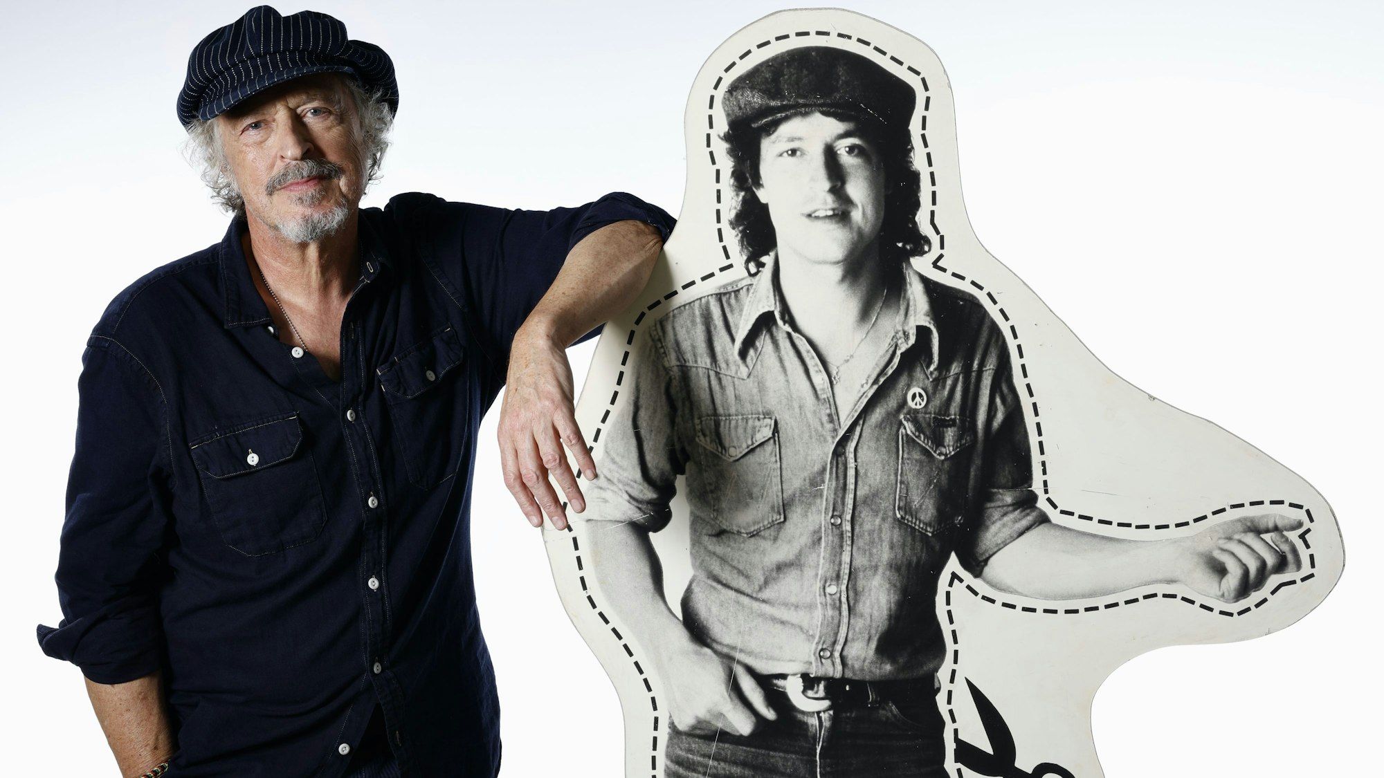 Wolfgang Niedecken steht neben einem Pappaufsteller, der ihn in jungen Jahren zeigt.