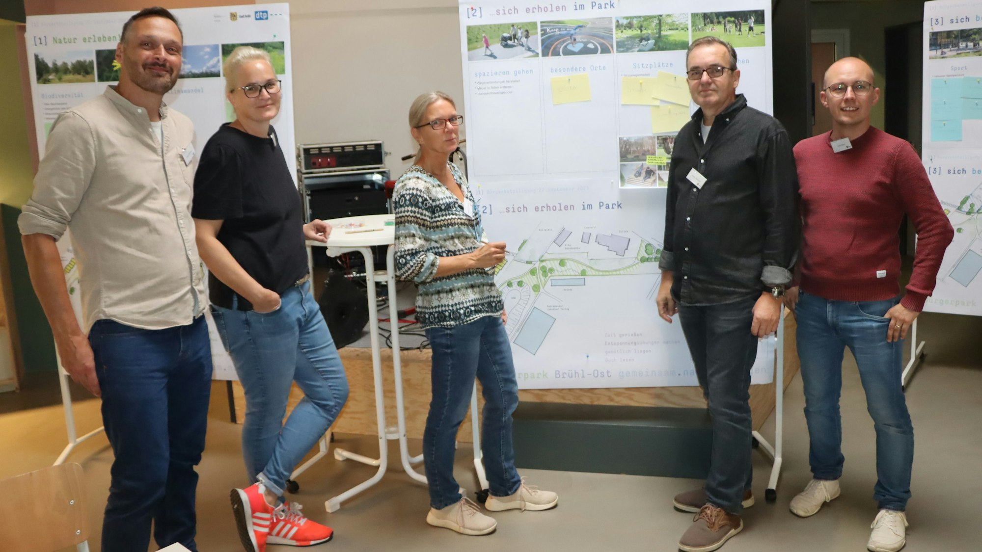 Zu sehen ist die Gruppe der Verantwortlichen vor Stellwänden, auf denen die Pläne für den Park angebracht sind.