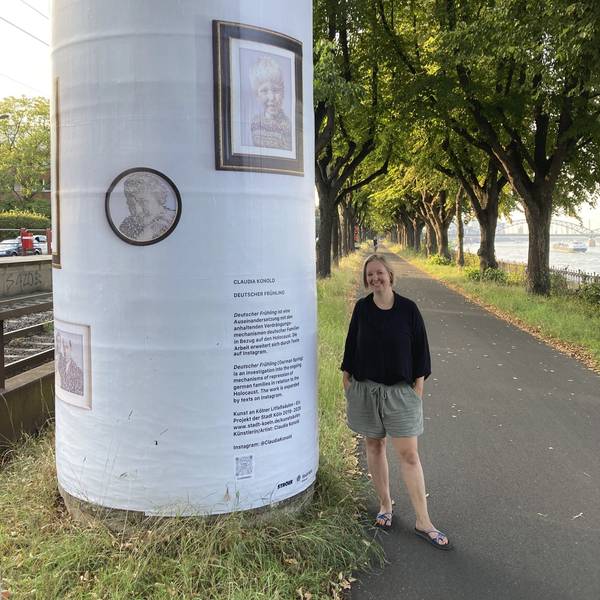 Eine Frau mit blondem Pagenkopf steht neben einer Litfaßsäule, die mit Texten und Bildern beklebt ist.