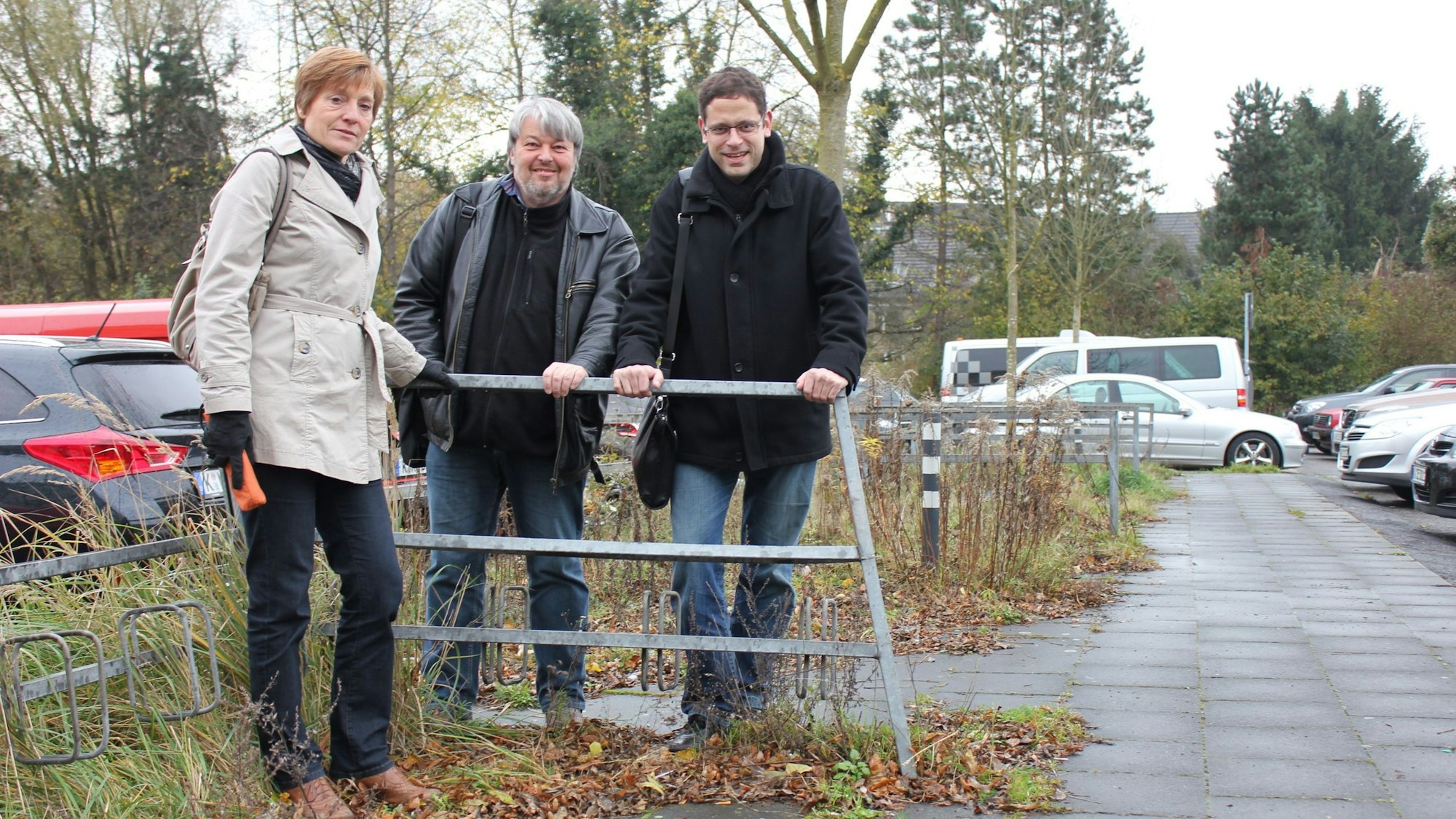 Eine Frau und zwei Männer stehen nebeneinander an einem Geländer.