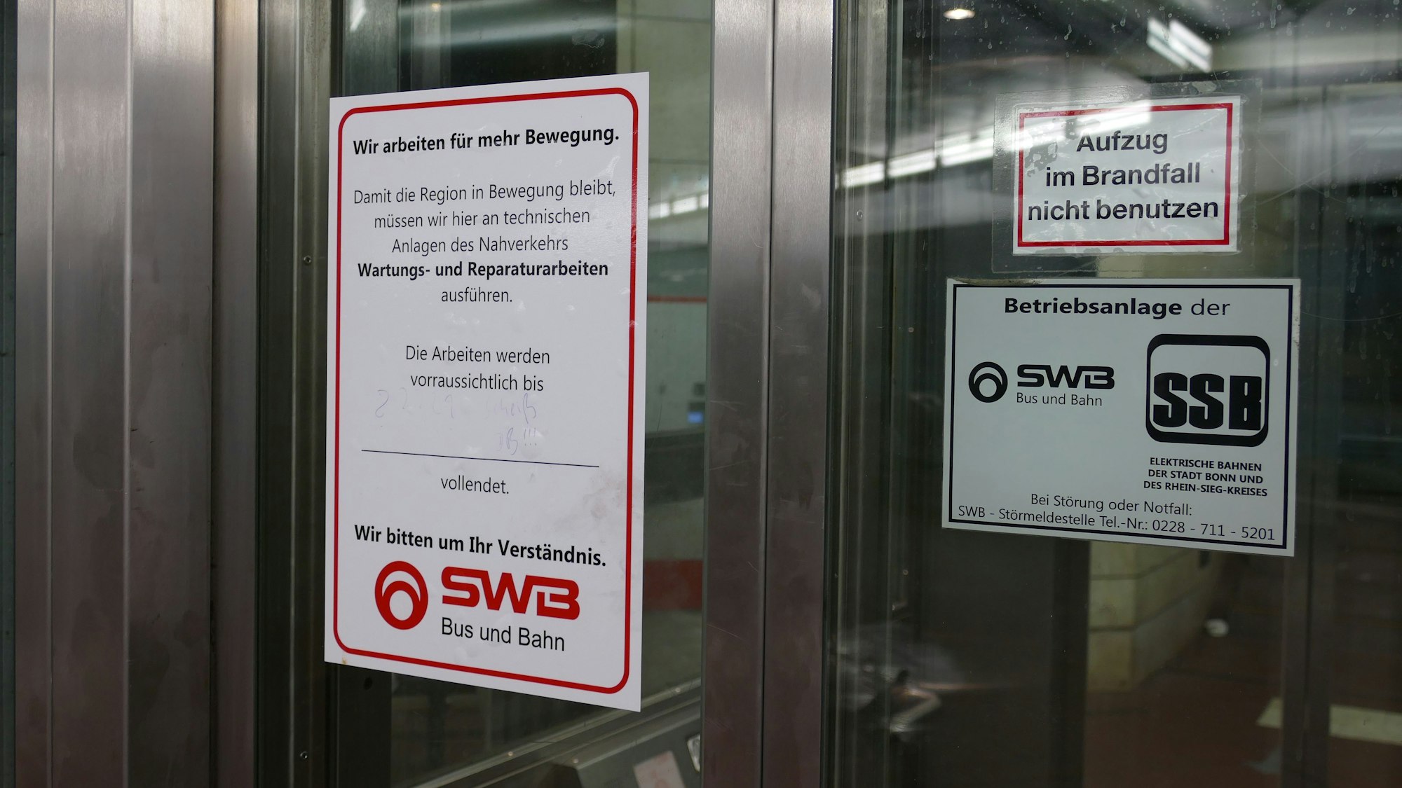 An der gläsernen Aufzugtür klebt ein Schild der SWB, das auf den Defekt und die anstehende Reparatur hinweist. Das Feld, in dem das Ende der Arbeiten eingetragen werden soll, ist allerdings leer.