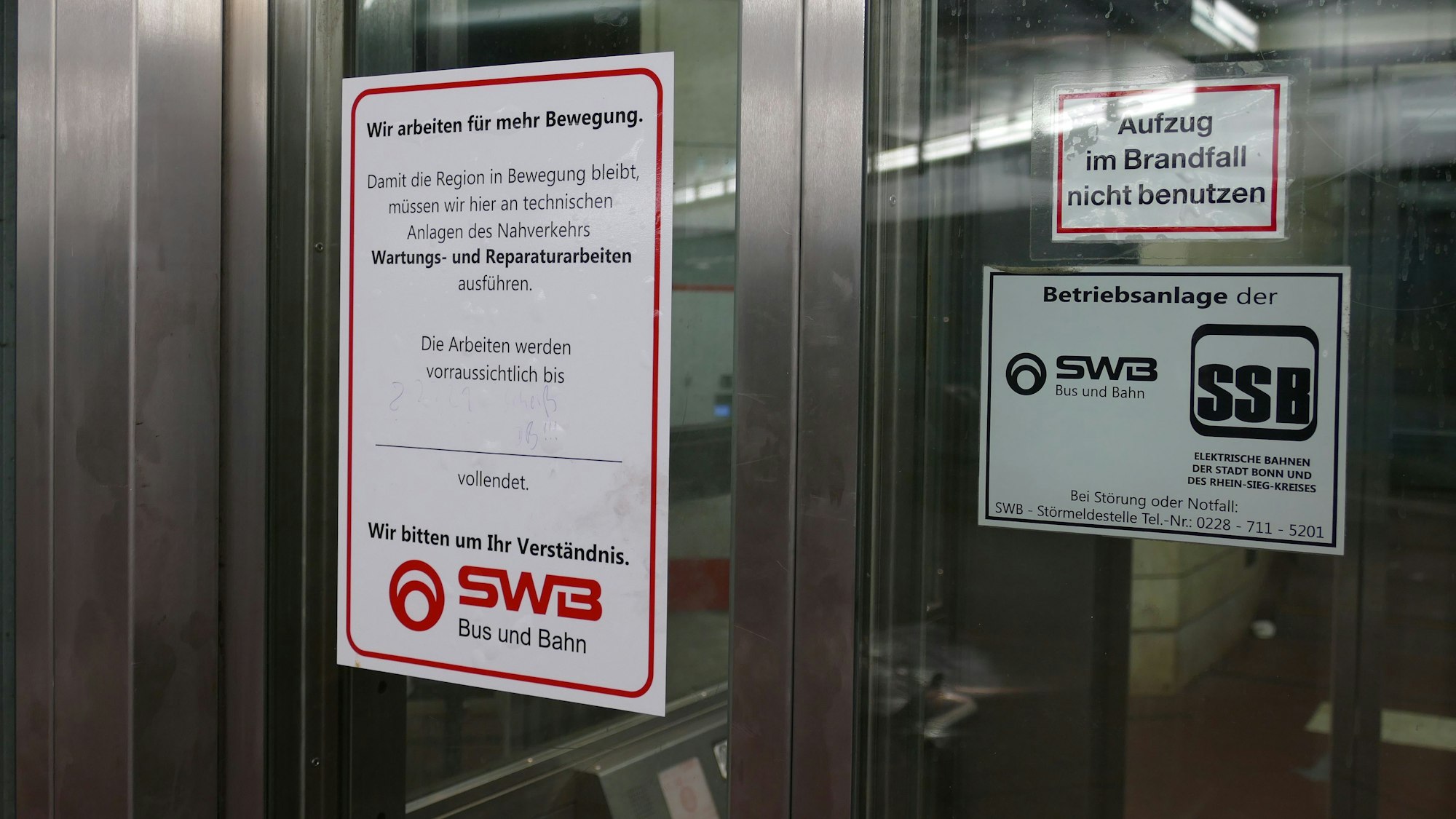 Ein Aufkleber der Stadtwerke Bonn klebt auf der gläsernen Aufzugtür.