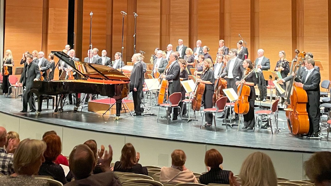 Orchester und Pianist stehen auf der Bühne.