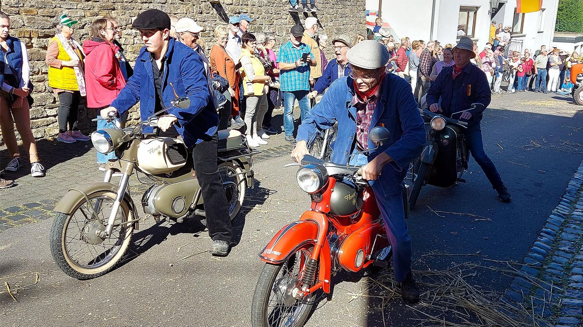 Vier Männer fahren auf alten Motorrädern durch den Ort.