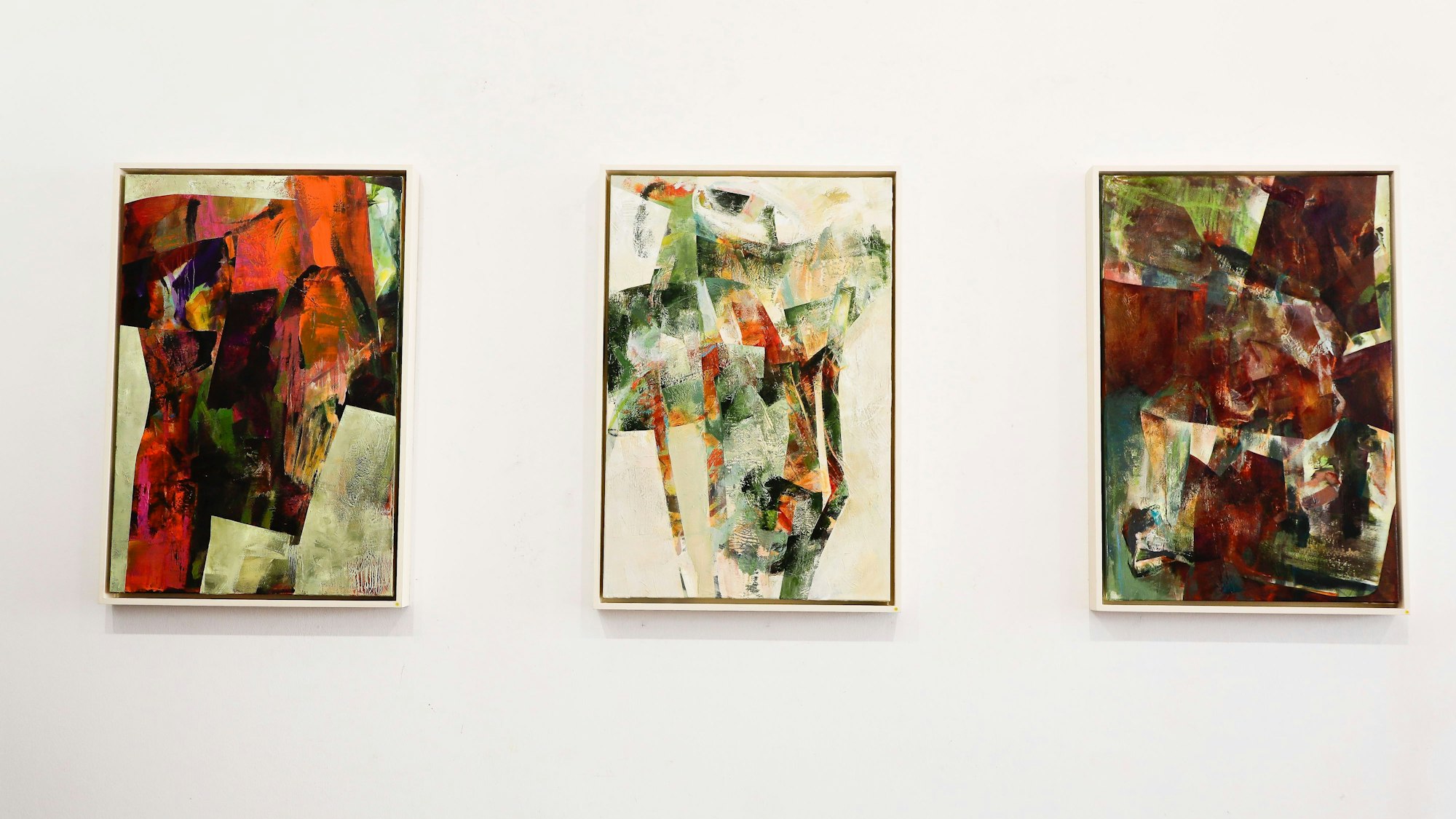 Drei abstrakte Bilder hängen an einer Wand.