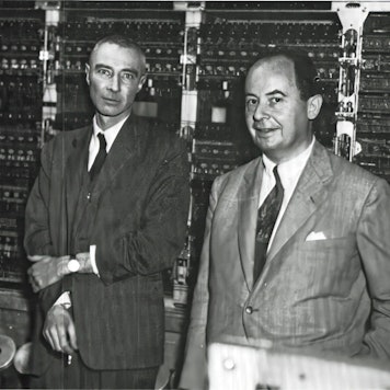 Robert Oppenheimer (links, mit Zigarette in der Hand) und John von Neumann stehen vor dem frühen Universalrechner „MANIAC“ im Keller des Institute for Advanced Study in Princeton.