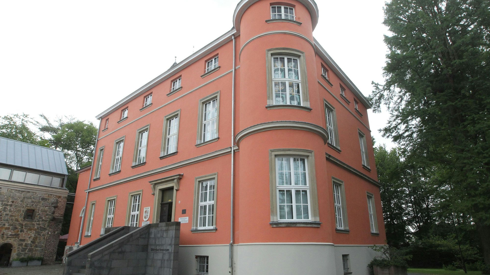 Die Burg Wissem mit ihrer rötlichen Fassade und einem Rundturm als Eckpunkt.