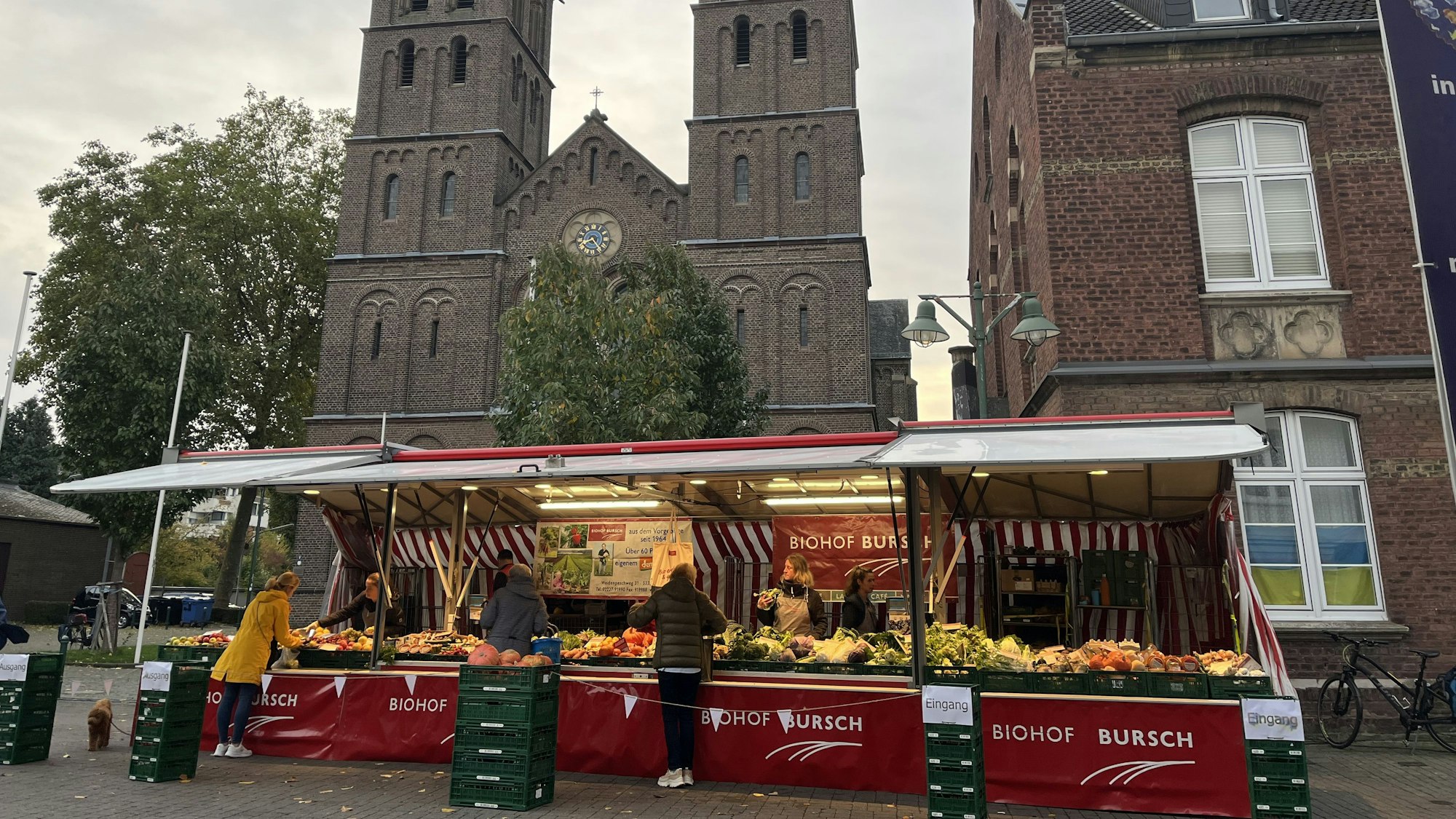 Ein Marktstand, im Hintergrund eine Kirche und ein Gebäude.