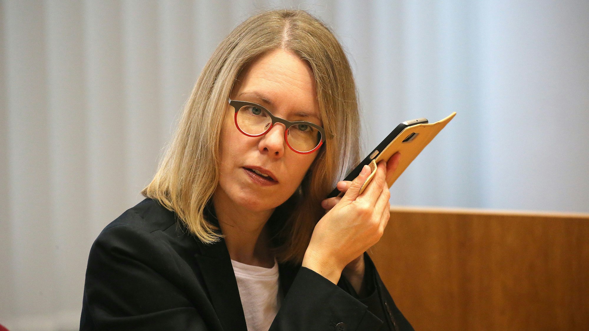 Anne Brorhilker, Oberstaatsanwältin hört im Landgericht in ihr Smartphone. Die Plädoyers im Prozess um Cum-Ex-Deals beginnen. +++ dpa-Bildfunk +++