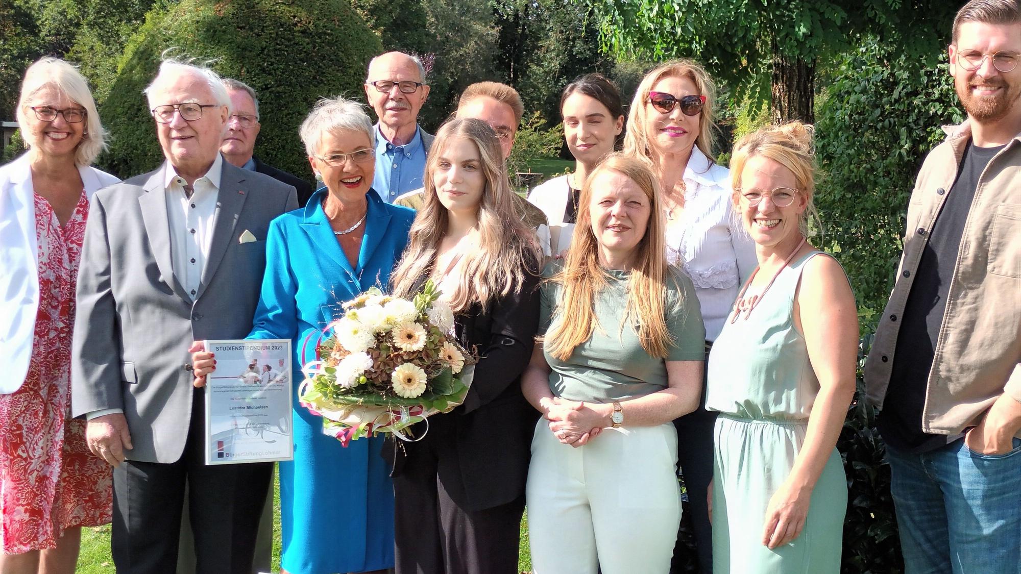 Zwölf Personen, in der Mitte eine junge Frau mit Blumenstrauß