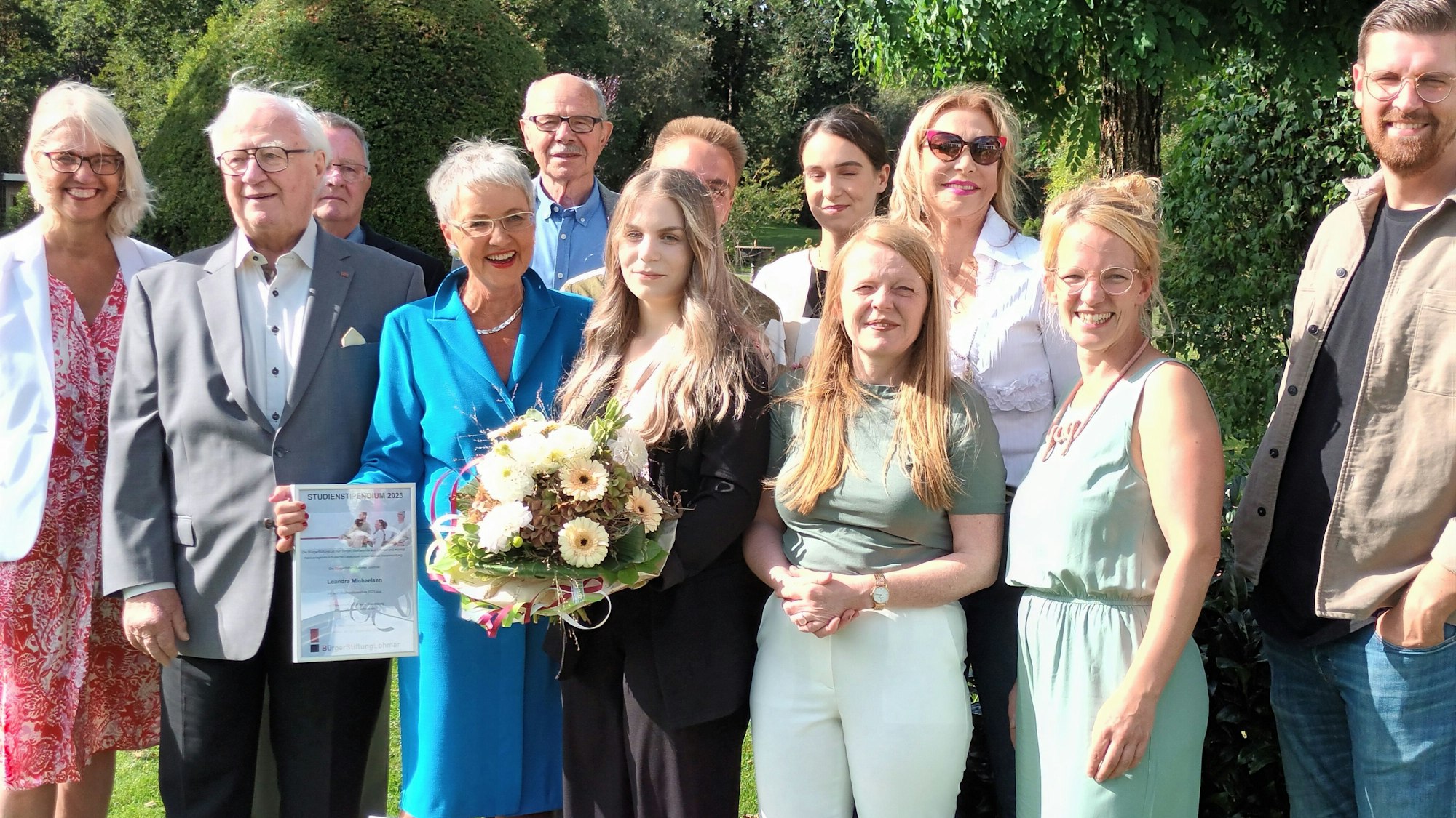 Zwölf Personen, in der Mitte eine junge Frau mit Blumenstrauß