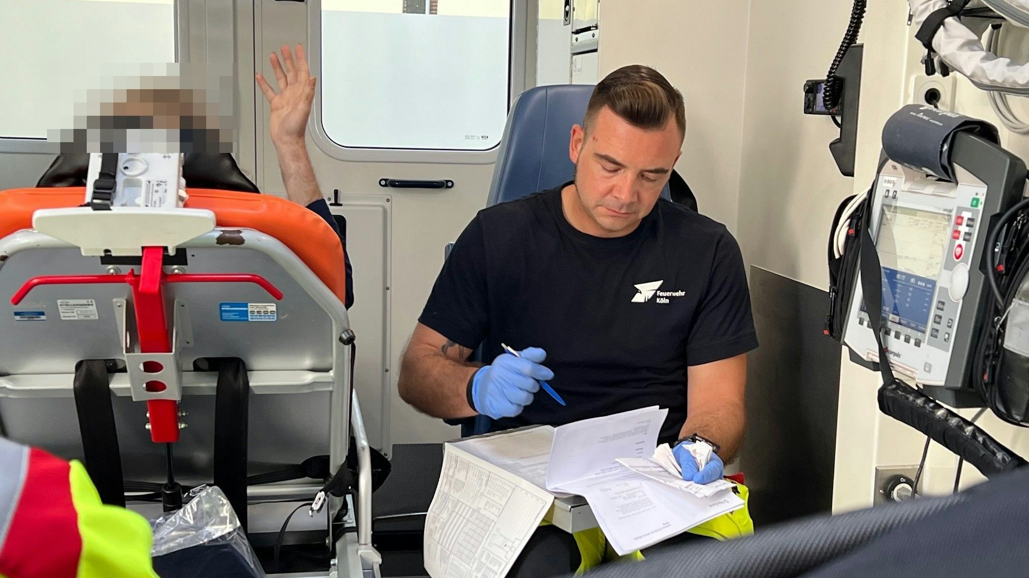 Markus Buth sitzt hinten im RTW neben dem Patienten, der auf einer Liege liegt.
