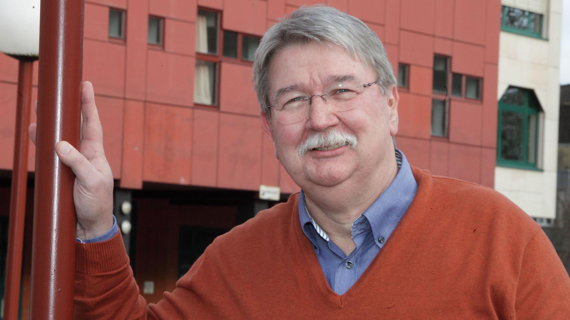 Werner Conrad lehnt an einem Gitter vor dem Bürgerhaus Bergischer Löwe in Bergisch Gladbach.