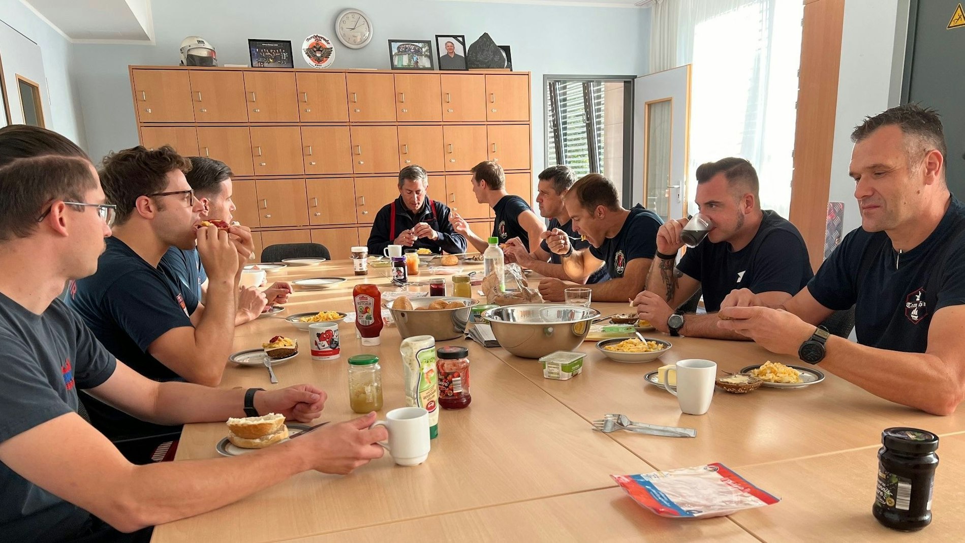 Feuerwehrmänner sitzen an einem Tisch und frühstücken.