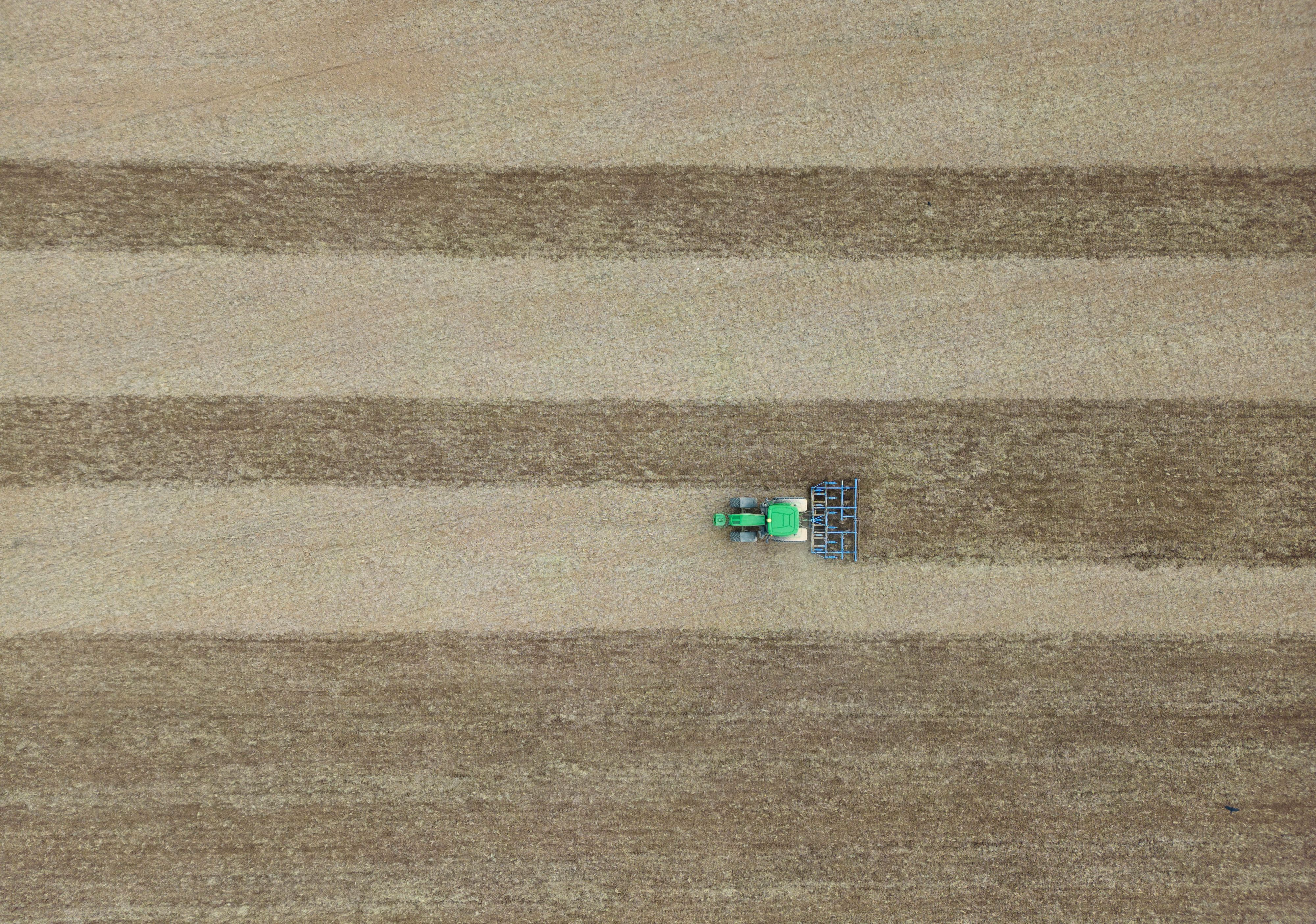 Eine Egge zieht dieser Landwirt hinter seinem Traktor über ein Feld.