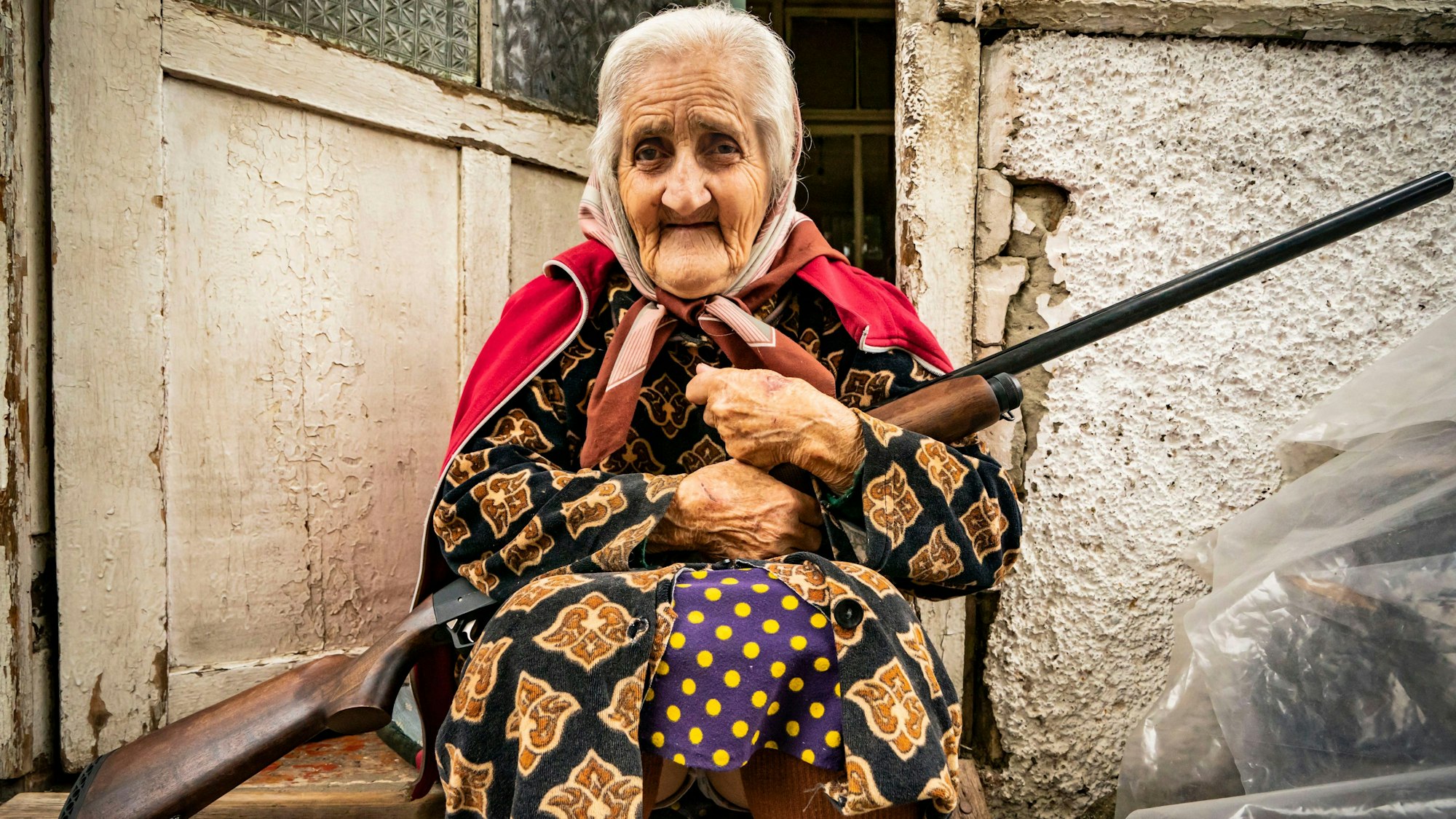 Eine alte Frau sitzt mit einem Gewehr im Eingang ihres Hauses, während die aserbaidschanische Armee die Stadt Stepanakert unter Beschuss nimmt.