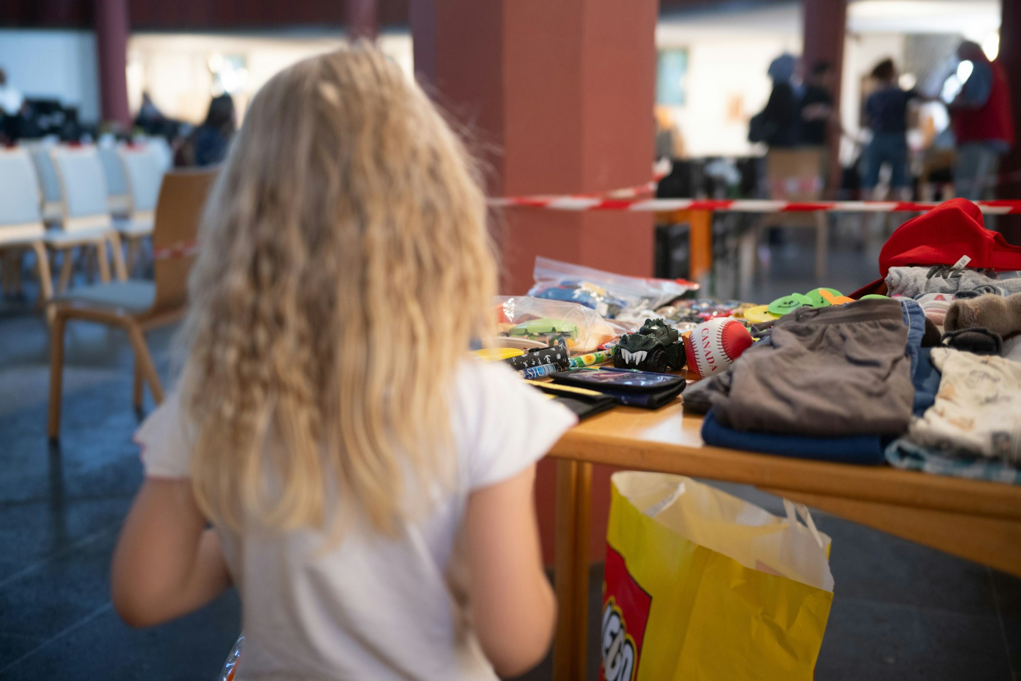 Kind Emilya steht während der Ausgabezeit in einer «Laib und Seele»-Ausgabestelle der Berliner Tafel in der evangelischen Paulus-Kirchengemeindean einem Tisch mit Spielzeug.