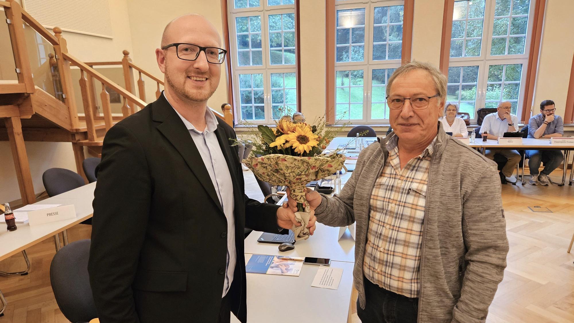 Bürgermeister Ingo Pfennings (l.) überreicht Gerd Breuer einen Blumenstrauß.