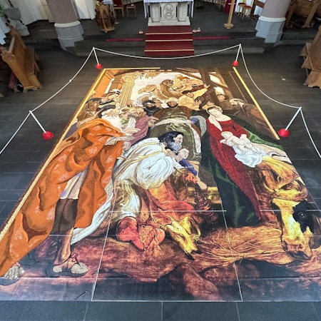 Auf dem Boden einer Kirche liegt das aus Körnern, Samen, Blüten und Hülsenfrüchten bestehende Erntedank-Bild.