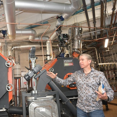 Zwei Heizungskessel sind zu sehen. Ein Mann steht daneben, um die Anlage zu erklären.