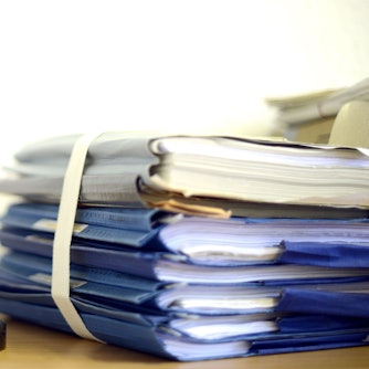 Eine modellhafte Nachbildung der Justitia steht im Raum eines Richters neben einem Holzhammer und einem Aktenstapel.