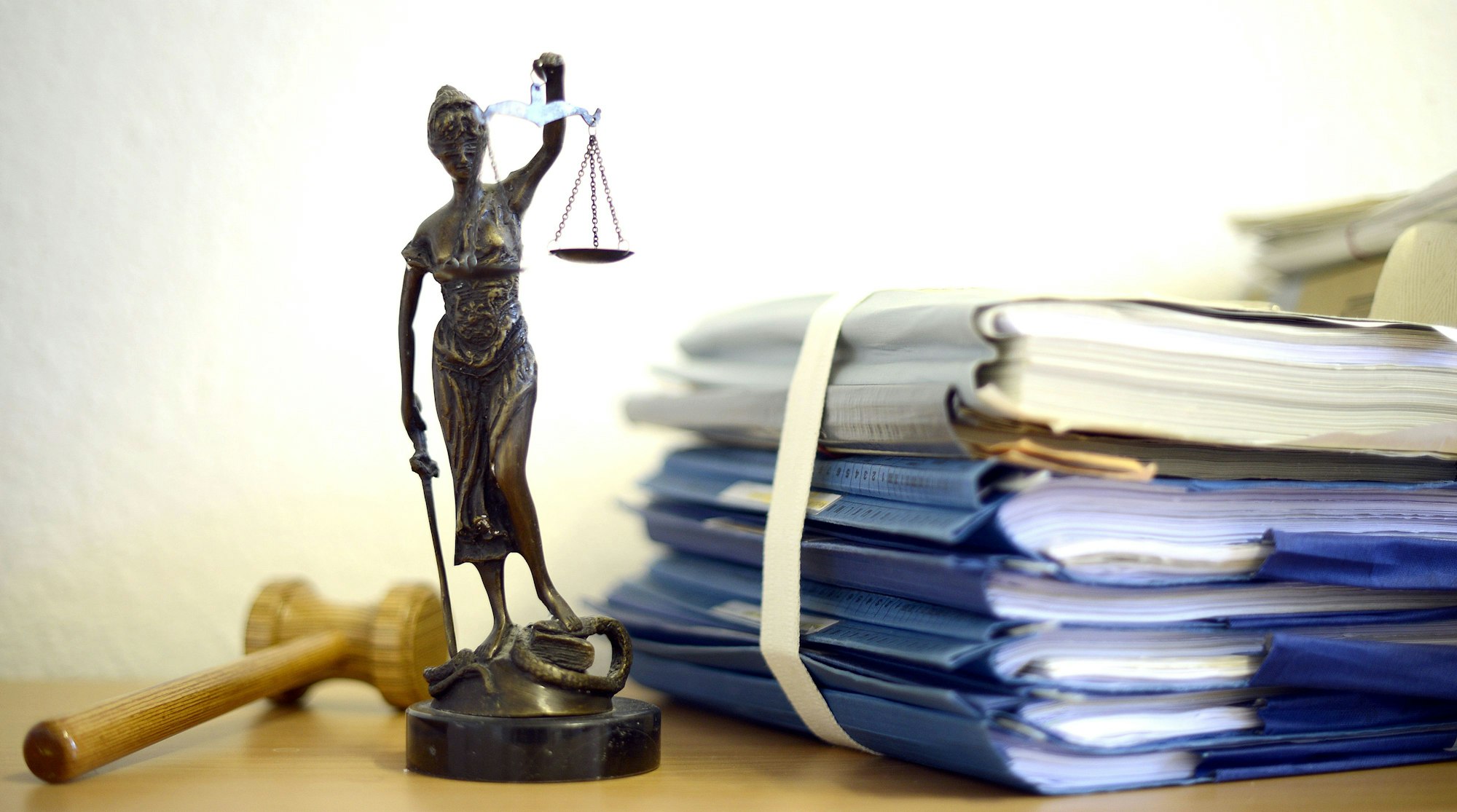 Eine modellhafte Nachbildung der Justitia stehtneben einem Stapel Akten.
