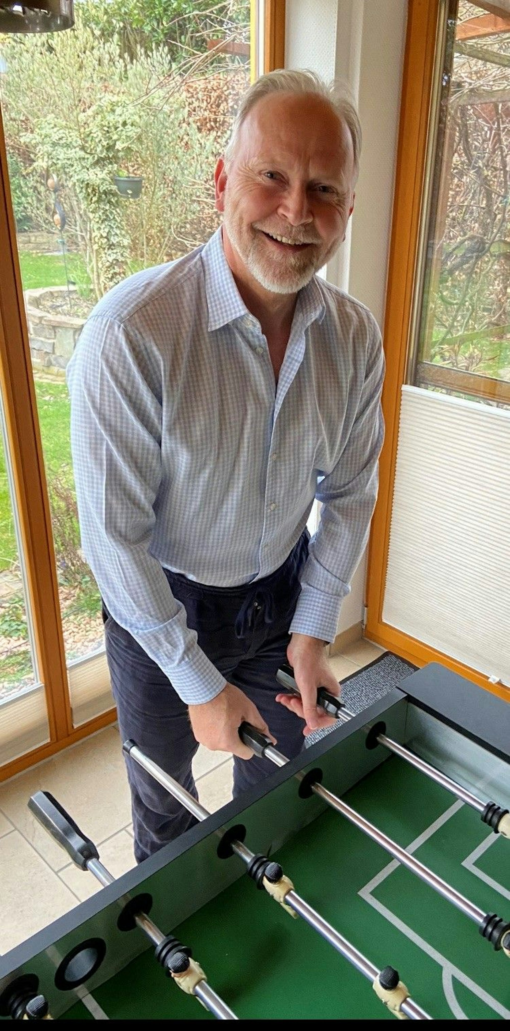 Auf dem Bild ist ein Mann an einem Tischkicker zu sehen.