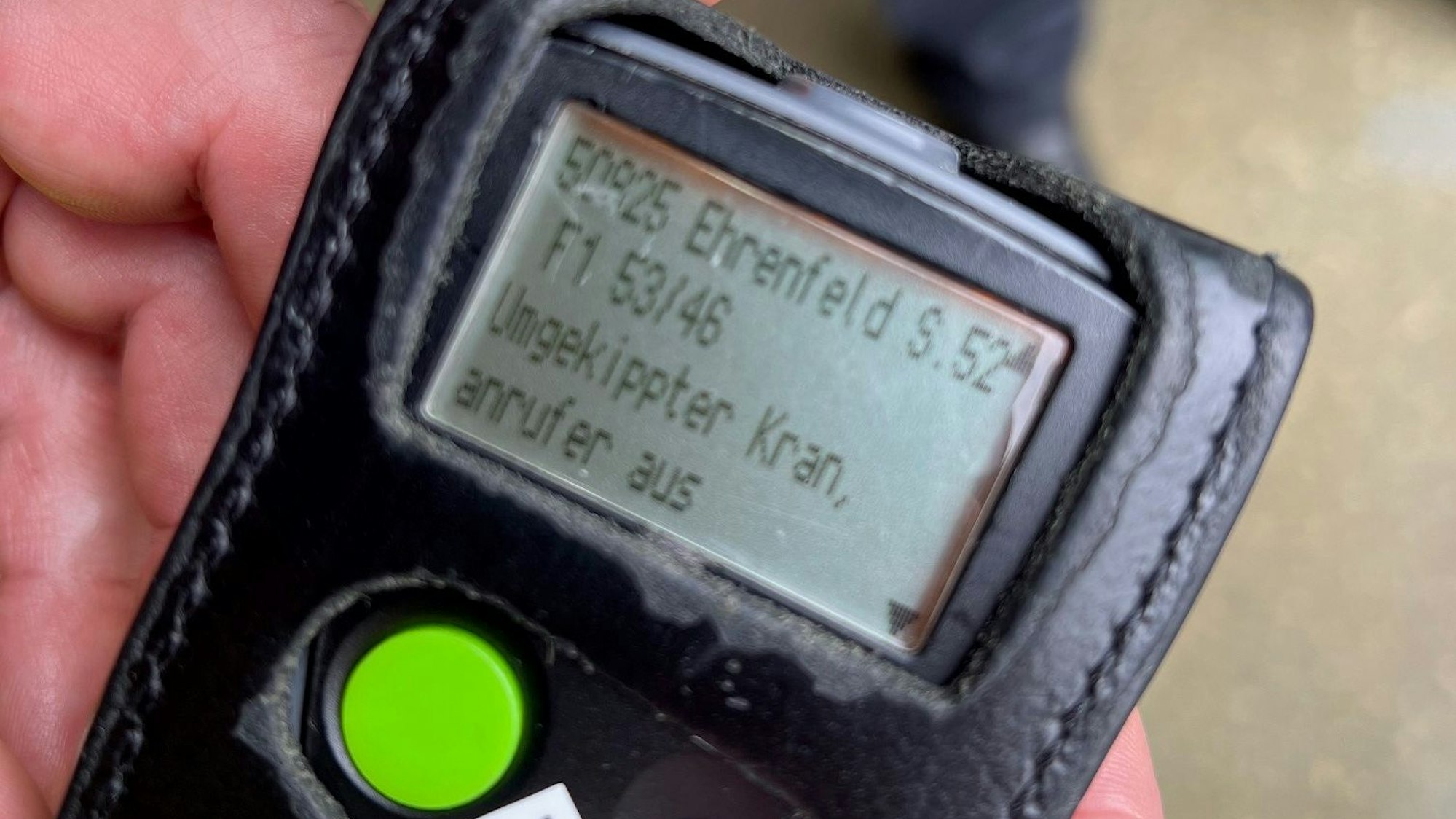 Auf dem Display eines Funkmelders steht: „Umgekippter Kran“.