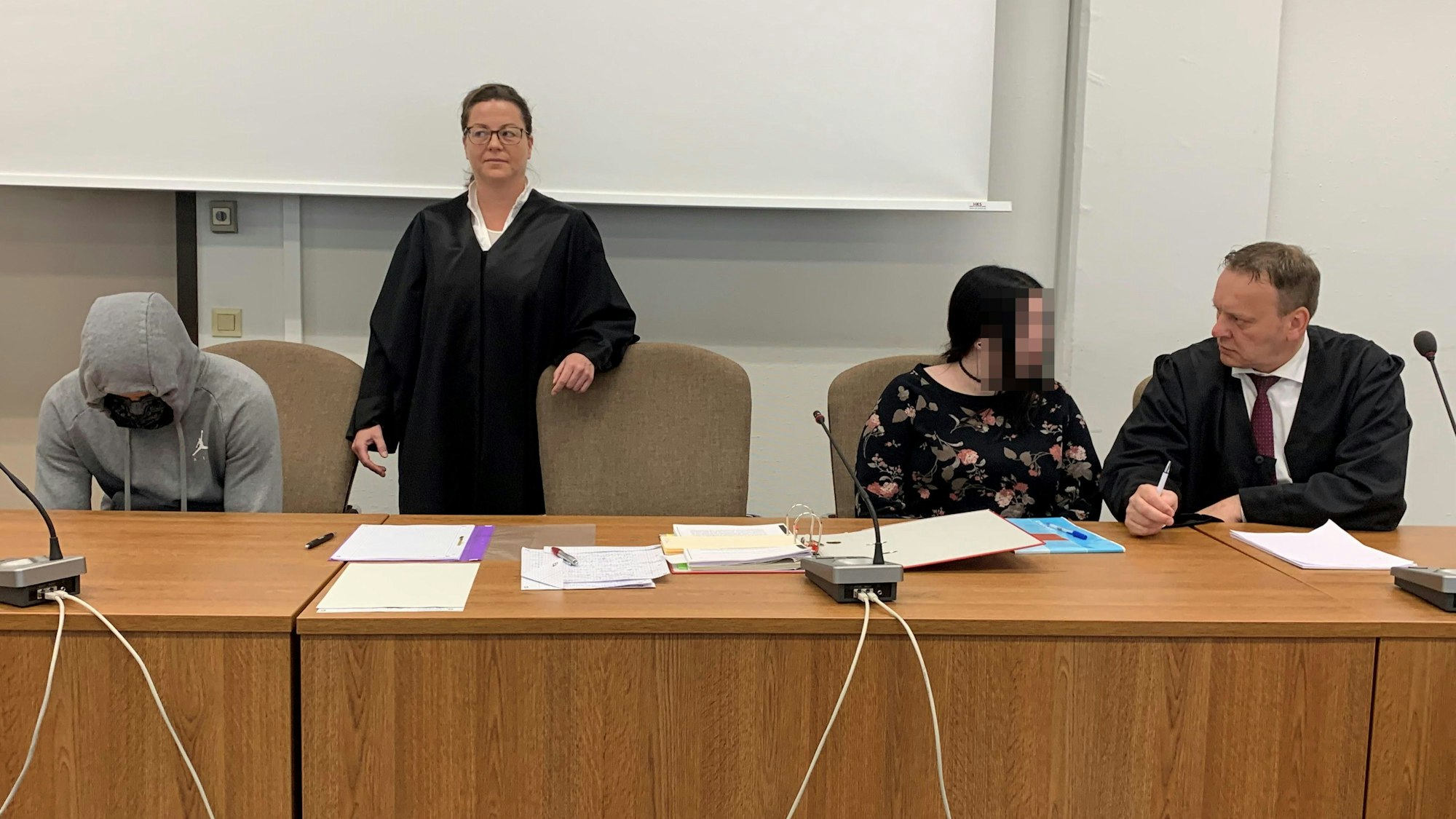 Das Bild zeigt die beiden Angeklagten mit ihren Verteidigern im Gerichtssaal.