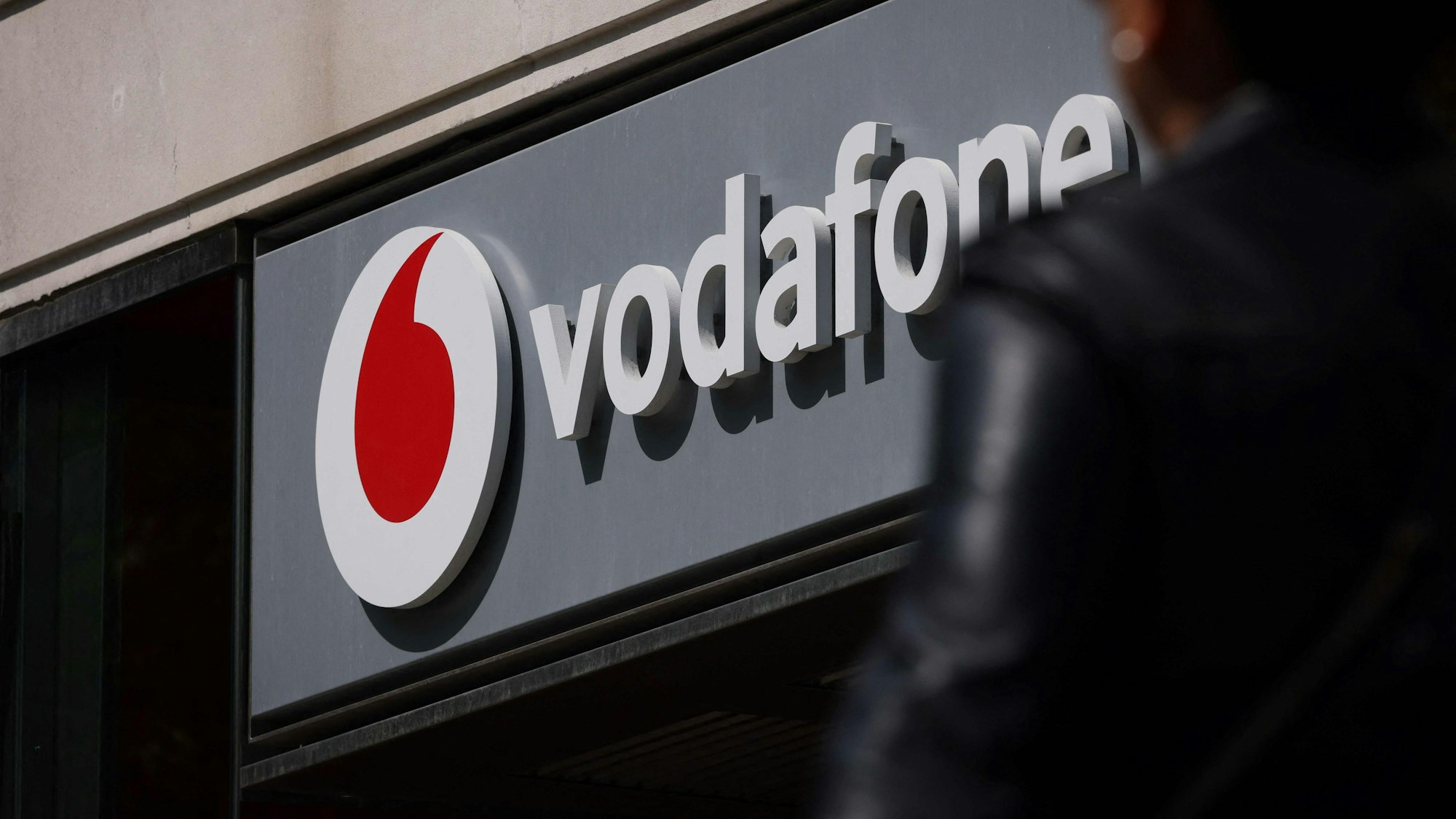 An einem Geschäft hängt ein Schild mit der Aufschrift „Vodafone“.